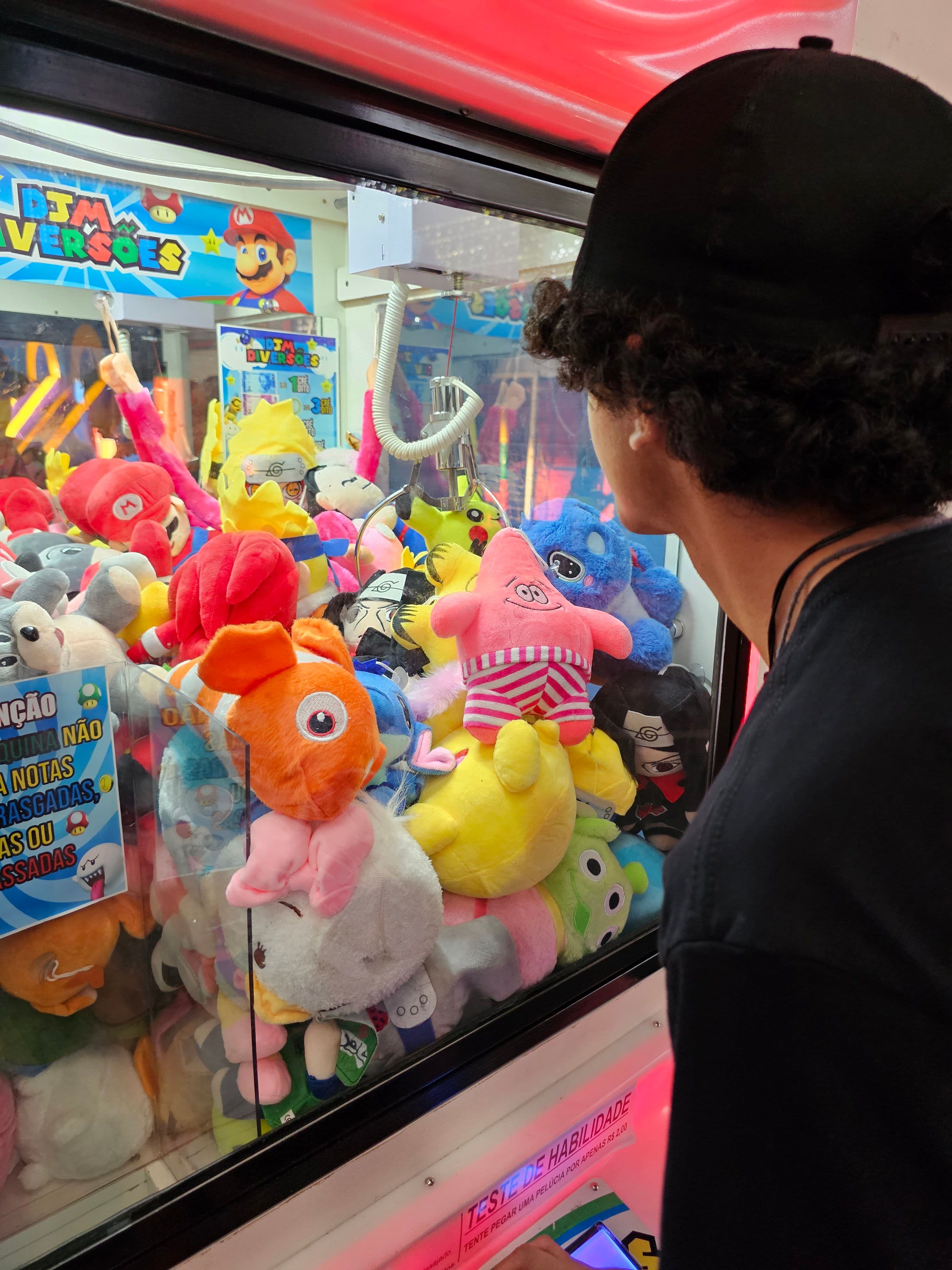 Jovem capturando pelúcia na máquina